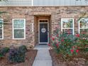 Close-up of stone facade, the front door with welcome sign, and manicured landscaping at 426 Kenwood Vw, Indian Trail, NC 28079