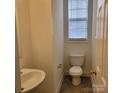 Cozy powder room with a pedestal sink, toilet, window, and neutral color scheme; clean and functional at 4612 Waterbell Ln, Waxhaw, NC 28173