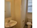 Bright powder room featuring a pedestal sink, toilet, mirror, and window; clean and well-lit space at 4612 Waterbell Ln, Waxhaw, NC 28173