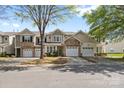 Street view of townhomes with stone accents, one-car garages, and landscaped front yards under a blue sky at 5959 Pale Moss Ln, Charlotte, NC 28269