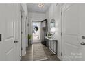 Inviting hallway with decor featuring a mirror, console table, and wood flooring leads to the open front door at 7172 Indigo Way, Denver, NC 28037