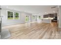 Open-concept living space with light wood floors, fireplace, and a kitchen with stainless steel appliances at 9940 Manor Vista Trl, Kannapolis, NC 28027