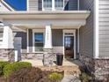 Inviting front porch with classic columns, stone accents, a decorative planter, and a beautiful front door at 1022 Doughton Ln, Indian Trail, NC 28079
