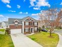 Two-story brick home features an attached garage, manicured lawn, and mature landscaping at 10223 Kelso Ct, Charlotte, NC 28278