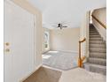Bright foyer with tiled floor, adjacent carpeted living space, and staircase with wood banister and white risers at 1102 Balcorn Pl, Charlotte, NC 28214