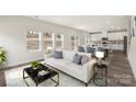 Bright living room featuring a plush white sofa, stylish décor, and an open floor plan leading into the kitchen at 117 Obadiah Ct, Troutman, NC 28115
