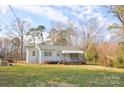 Quaint one-story home with a covered front porch, surrounded by a green lawn and mature trees at 1404 Lane Rd, Mount Holly, NC 28120