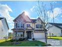 Inviting two-story home with stone and siding exterior, a manicured lawn, and a sunny sky at 4253 Stream Dale Nw Cir, Concord, NC 28027
