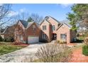 Stunning brick home featuring a well-manicured lawn, 3 car garage and lush landscaping against a bright blue sky at 4858 Sagittarius Cir, Denver, NC 28037
