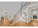 Elegant foyer with hardwood floors, staircase, white trim, and decorative table with round mirror at 5114 Morrowick Rd, Charlotte, NC 28226