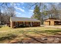 A well-maintained brick home with classic design, complemented by a lush green lawn and a quaint detached structure at 11018 Despa Dr, Mint Hill, NC 28227