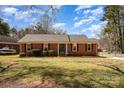 Charming single-story brick home with manicured lawn and mature trees, bathed in the warm glow of daylight at 11018 Despa Dr, Mint Hill, NC 28227