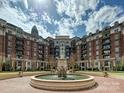 Elegant water fountain sits centered in front of brick apartments under a partly cloudy sky at 300 W 5Th St # 402, Charlotte, NC 28202