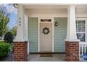 Inviting front porch features brick accents, white columns, and a charming wreath on the front door at 464 Hurston Cir, Charlotte, NC 28208