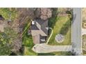 Aerial view of home showcasing roof, yard, patio with fire pit, driveway, and tree-lined property at 7510 Plumcrest Ln, Harrisburg, NC 28075
