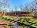 Classic red brick home with a welcoming walkway and mature trees creating a serene setting at 207 Oak Dr, Belmont, NC 28012