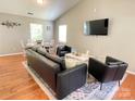 Cozy living room featuring hardwood floors, a black leather couch, and neutral color scheme at 218 Cottonwood Park Dr, Charlotte, NC 28214
