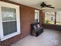 Cozy covered porch with brick walls, ceiling fan, and comfortable seating area with pillows at 312 Gold Hill Ave, Rockwell, NC 28138