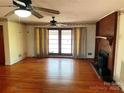 Spacious living room with hardwood floors, a brick fireplace, large windows with curtains, and a vintage ceiling fan at 501 Neelys Creek Rd, Rock Hill, SC 29730