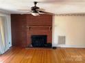 Open living area features polished hardwood floors and a red brick fireplace, creating a cozy focal point at 501 Neelys Creek Rd, Rock Hill, SC 29730