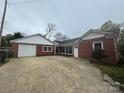 Rear exterior view of brick home with driveway, white garage door, and mature trees at 603 E Main St, Rock Hill, SC 29730