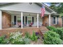 Inviting covered front porch with red brick base, decorated with potted plants and patio furniture at 8509 Anette Ave, Mint Hill, NC 28227