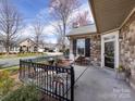 Inviting front porch featuring a stone facade, black shutters, wrought iron railing and outdoor seating at 864 Ledgestone Ct, Fort Mill, SC 29708