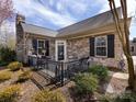 Inviting front porch featuring a stone facade, black shutters, wrought iron railing and outdoor seating at 864 Ledgestone Ct, Fort Mill, SC 29708