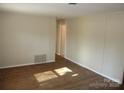 Empty living room with wood flooring and beige walls, bathed in sunlight streaming from a window at 1138 Choyce Ave, Charlotte, NC 28217
