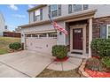 Home exterior featuring a two-car garage, a front door with stone accents, and mature landscaping at 12302 Volusia Ct, Charlotte, NC 28262