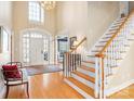 Grand foyer boasts soaring ceilings, hardwood floors, and a staircase with white railings at 6510 Seton House Ln, Charlotte, NC 28277