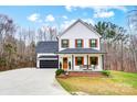 Beautiful two-story white farmhouse exterior with inviting front porch, black trim, and manicured landscaping at 693 Luther Dr, Iron Station, NC 28080