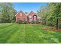 Beautiful red brick home with a manicured lawn, mature landscaping and a charming, symmetrical facade at 727 Mayfield Ct, Fort Mill, SC 29715