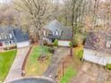 An aerial view of a landscaped suburban home with a two-car garage, surrounded by mature trees at 9238 Heritage Woods Pl, Charlotte, NC 28269