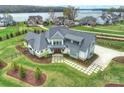 Aerial view of a luxurious modern farmhouse nestled by the lake with meticulous landscaping at 101 S Shore Dr, Belmont, NC 28012