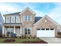 Charming two-story brick home with a manicured lawn and inviting front porch with rocking chairs at 13943 Penbury Ln # 376, Charlotte, NC 28278