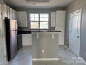 Modern kitchen featuring white cabinets, stainless refrigerator, and granite countertop island at 1634 Walnut View Dr, Charlotte, NC 28208