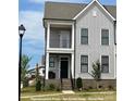 Charming two-story townhome with gray siding, black window frames, a covered porch, and a brick foundation at 19732-A School St, Cornelius, NC 28031