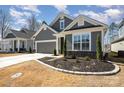 Well-manicured lawn featuring a gray single Gathering home with white trim, a garage, and easy driveway access at 7056 Cornwallis Ct, Iron Station, NC 28080