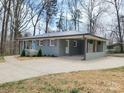 View of updated front exterior with a light-gray brick, newly planted landscaping, and convenient covered carport at 112 Greentree Dr, Mount Holly, NC 28120