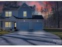 Charming two-story home featuring a two car garage and a well lit driveway, set against a picturesque twilight sky at 126 Orville Rd, Statesville, NC 28677