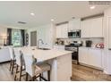 Kitchen with white cabinets, stainless appliances, center island with seating, and hardwood floors at 13011 Hampton Bay Ln, Charlotte, NC 28262