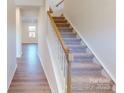 Bright stairway features carpeted steps, white risers and wood railing, leading to a hallway with hardwood floors at 1829 Augustine St, Monroe, NC 28112