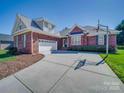 Brick home featuring a two-car garage, well-manicured lawn, and a long driveway at 108 Avaclaire Way, Indian Trail, NC 28079