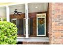 Inviting front porch with brick columns, ceiling fan, and decorative wreath on the front door at 1120 Millwright Ln, Matthews, NC 28104