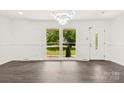 Bright living room with refinished hardwood floors, modern light fixture, and large window showcasing a manicured front yard at 1316 Fox Run Dr, Charlotte, NC 28212