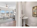 Stylish powder room featuring pedestal sink, round mirror, and an open view of the living room at 1435 Mammoth Rd, Hickory, NC 28602