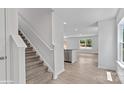 A bright entryway showcasing a carpeted staircase, vinyl flooring, and an open view into the kitchen and living area at 1439 Mammoth Rd, Hickory, NC 28602