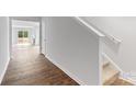 Bright hallway featuring wood flooring, white walls, with staircase and an open view of the living area at 3016 Sassafras Trl, Gastonia, NC 28056