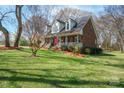 Brick home with front porch, dormers, green lawn, landscaping and an American flag on display at 4436 Roberta Rd, Concord, NC 28027